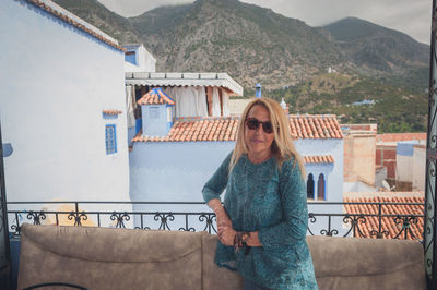 Portrait of mature woman standing against buildings and mountains