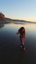 Boy playing on beach against clear sky