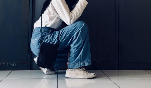 Low section of man sitting on floor against wall