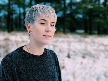 Portrait of thoughtful young woman standing in forest during winter