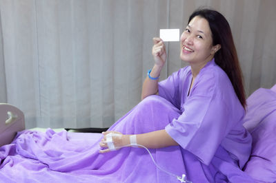 Portrait of a smiling young woman sitting on bed