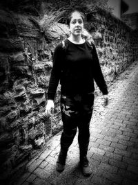 Portrait of teenage girl standing against wall