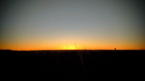 Scenic view of silhouette field against sky during sunset