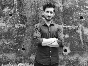 Portrait of young man standing against wall