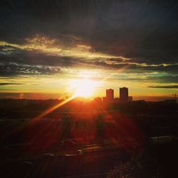 Sun shining through clouds over city