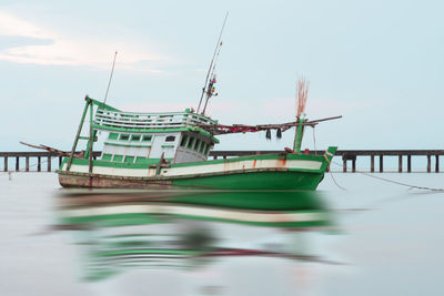 Fishing boat moored in sea against sky