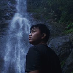 Portrait of young man looking away in forest