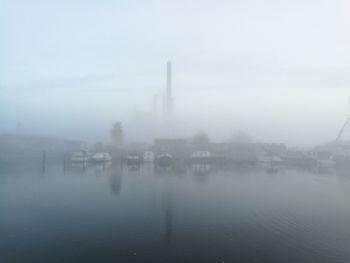 Scenic view of foggy weather against sky during winter