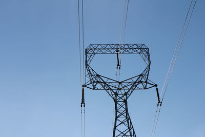 Low angle view of electricity pylon against clear sky