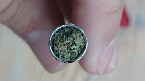 Close-up of cropped hand holding marijuana in smoking pipe