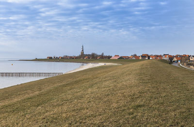 House on town by sea against sky