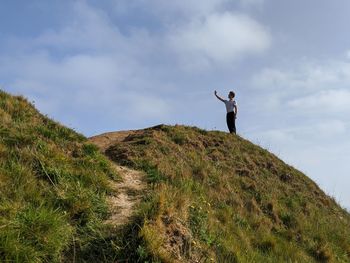 Low angle view of man standing on mountain against sky