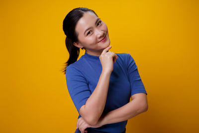 Portrait of a smiling young woman against yellow background