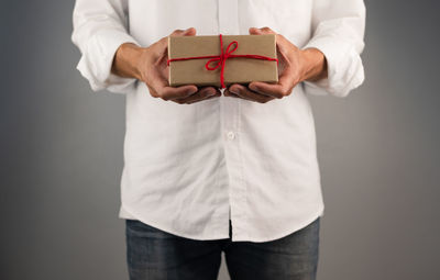 Midsection of man holding hands against white background