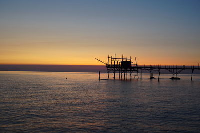 Silhouette ship in sea against sky during sunset