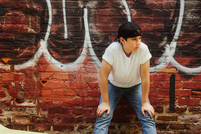 Full length of young man standing against brick wall