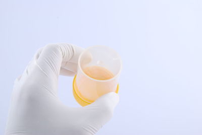 Close-up of hand holding tea cup against white background