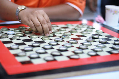Midsection of man playing bottle cap checkers