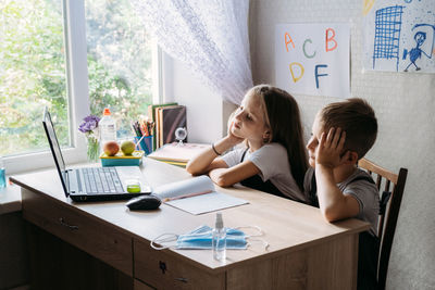 Schoolkids boy and girl using laptop for online study during homeschooling at home. homeschooling