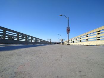 Road by bridge against clear blue sky