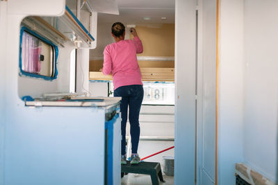 Rear view of woman painting in camper trailer