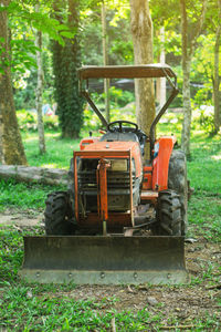 Tractor on field against trees in forest