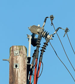 Low angle view of telephone pole against clear blue sky