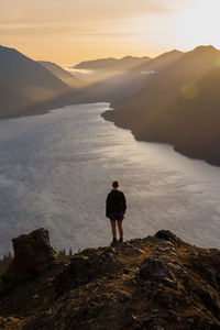 Rear view of man standing on rock by sea