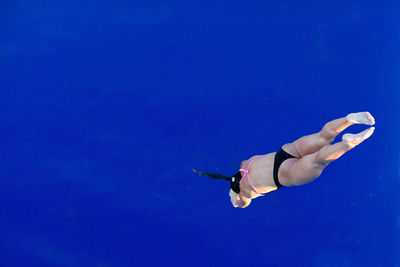 High angle view of mid adult woman wearing bikini while jumping in swimming pool