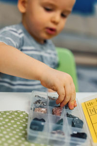 Close-up of boy putting stone in container