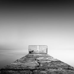 Pier amidst clear sea against sky during foggy weather