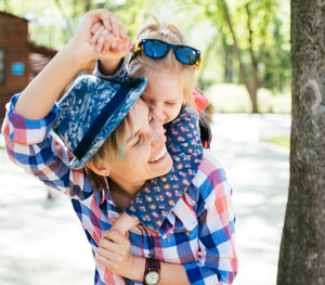 Close-up smiling mother giving piggyback ride to daughter