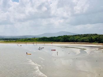 Group of people on beach against sky