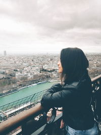 Rear view of woman looking at cityscape against sky