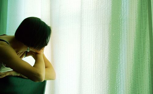 Side view of woman against curtain