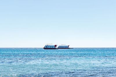 Ship sailing on sea against clear sky