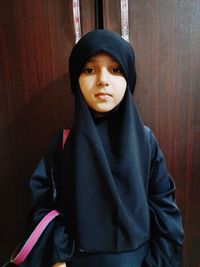 Portrait of beautiful young woman standing against wall