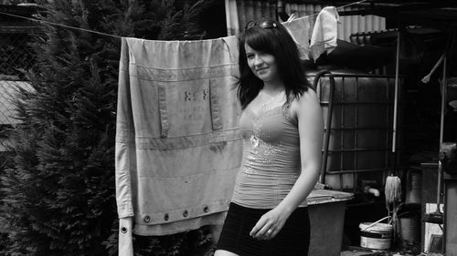 Portrait of young woman standing by fabric hanging on rope