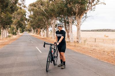 Woman with bicycle standing on road