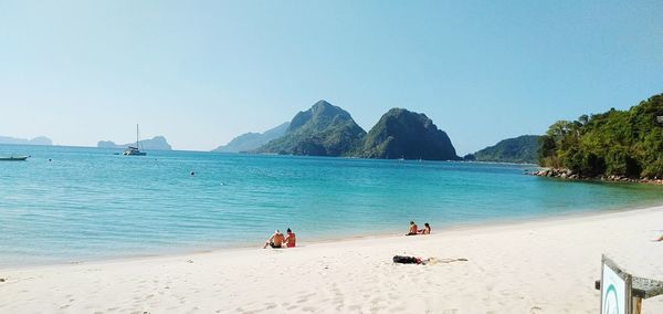 People on beach against clear sky