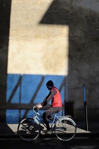 Side view of man riding bicycle against wall
