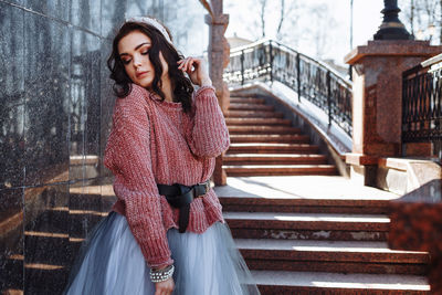 Young woman standing against steps