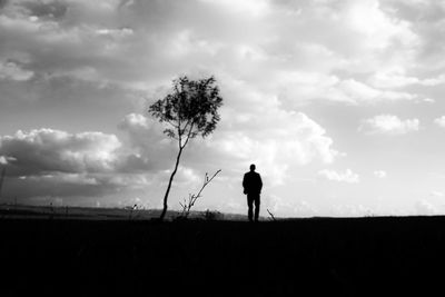 Silhouette man standing on field against sky