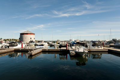 Boats moored at harbor against sky