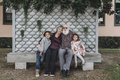 Portrait of grandparents sitting with cute twin grandchildren outside