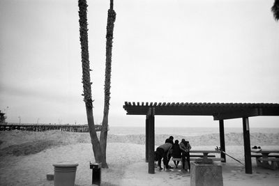 People sitting on beach by sea against sky