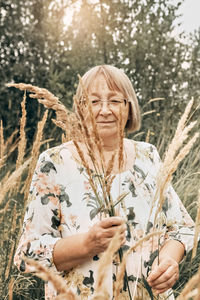 Portrait of woman holding plant in forest