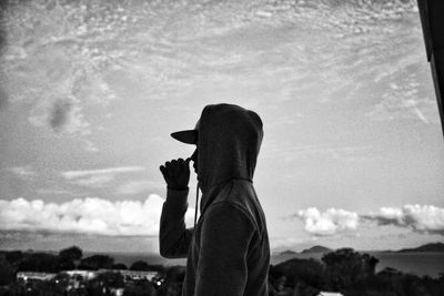 Silhouette man feeding horse against sky