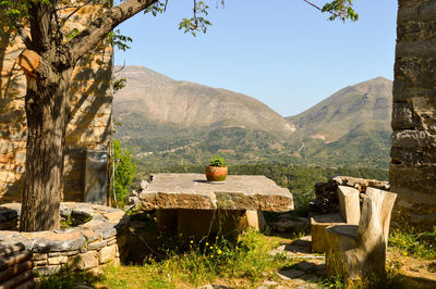 Wooden chairs by stone table against mountains