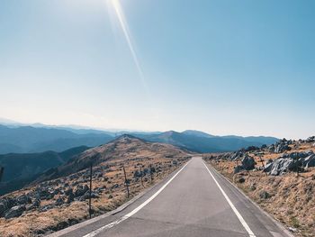 Road leading towards mountains against sky